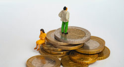 Deux personnages miniatures l'un assis et l'autre debout sur des pièces de monnaie en euros.