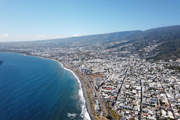 Paysage en vue plongée sur la côte, la ville, les pentes de la montagne, l'horizon et le ciel bleu