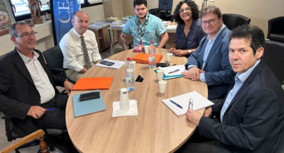 Dans un bureau., six personnes posent autour d'une table ovale pour la photo.