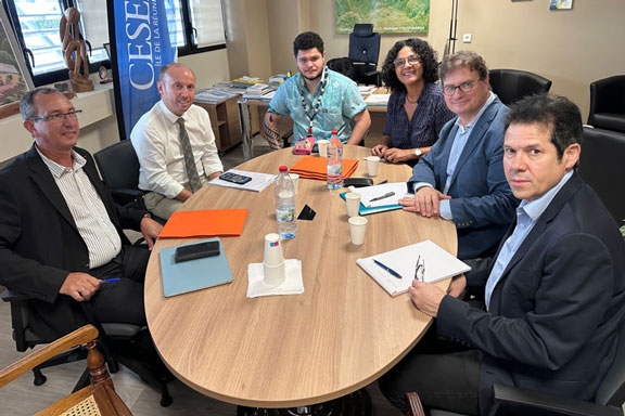 Dans un bureau., six personnes posent autour d'une table ovale pour la photo.