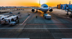 Couché de soleil sur le tarmak d'un aéroport avec un avion garé vu de face.