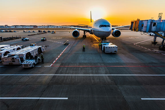 Couché de soleil sur le tarmak d'un aéroport avec un avion garé vu de face.