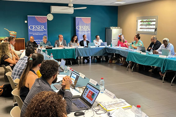 Dans une salle de réunion, des personnes sont assisent autour d'une table en U
