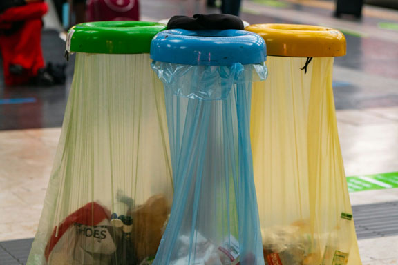 Photographie de trois poubelles de tri, une verte, une bleu et une jaune