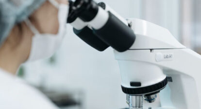 Laborantin·e regardant dans un microscope