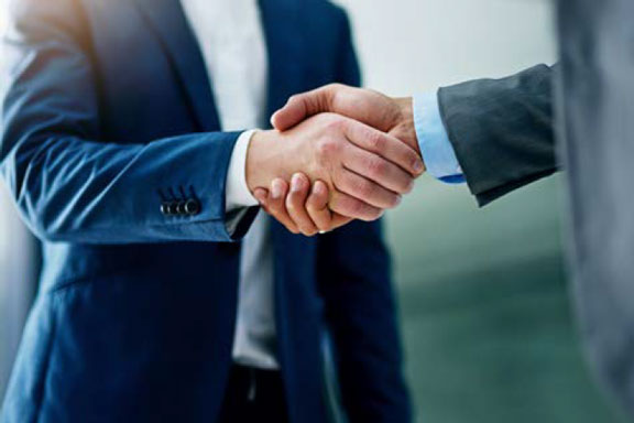 Photo cadrée sur les mains serrées de deux personnages en costume deux pièces