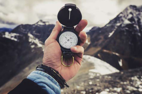Boussole dans une main sur fond de paysage montagnard