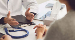 Photo cadrée sur les mains d'un médecin discutant avec deux personnes à un bureau